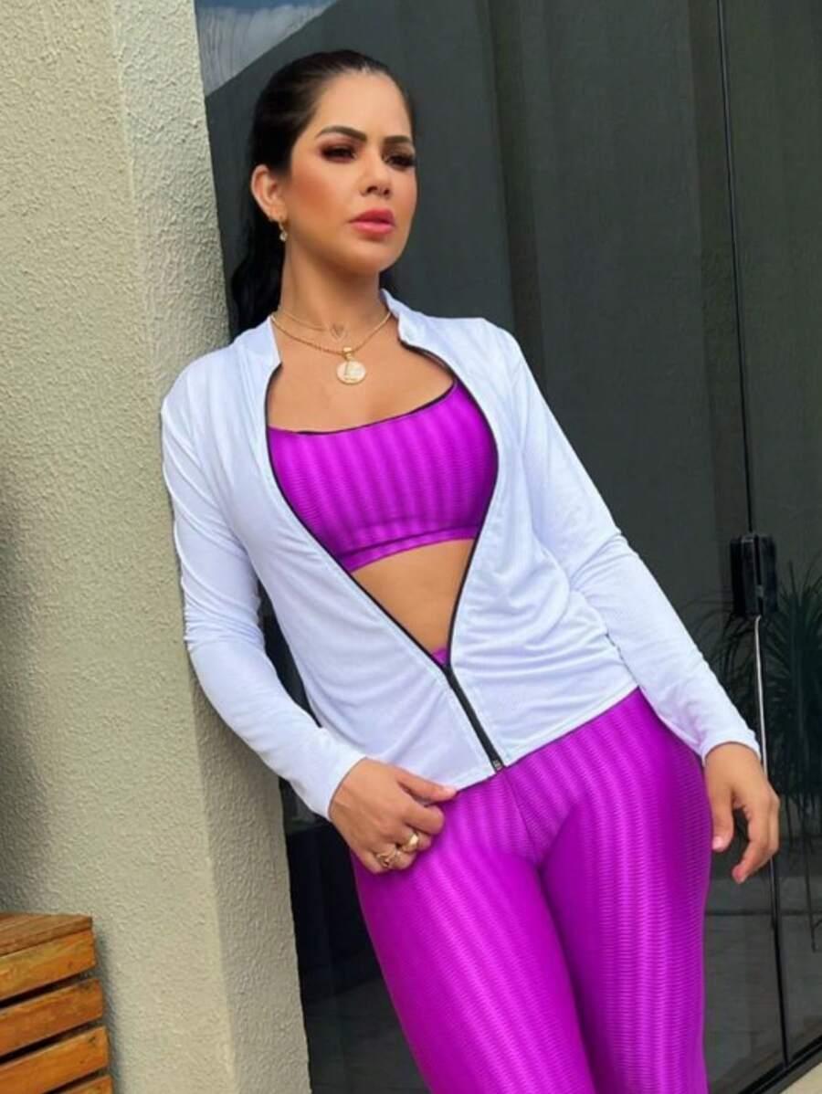 Mulher vestindo casaco branco fosco com zíper aberto, top e legging roxos, em fundo branco fosco