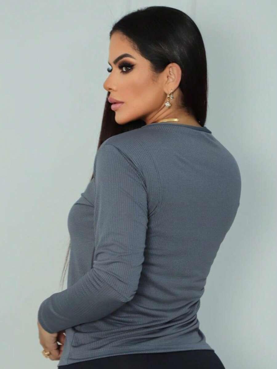 Mulher de costas com blusa cinza de manga longa em fundo branco fosco