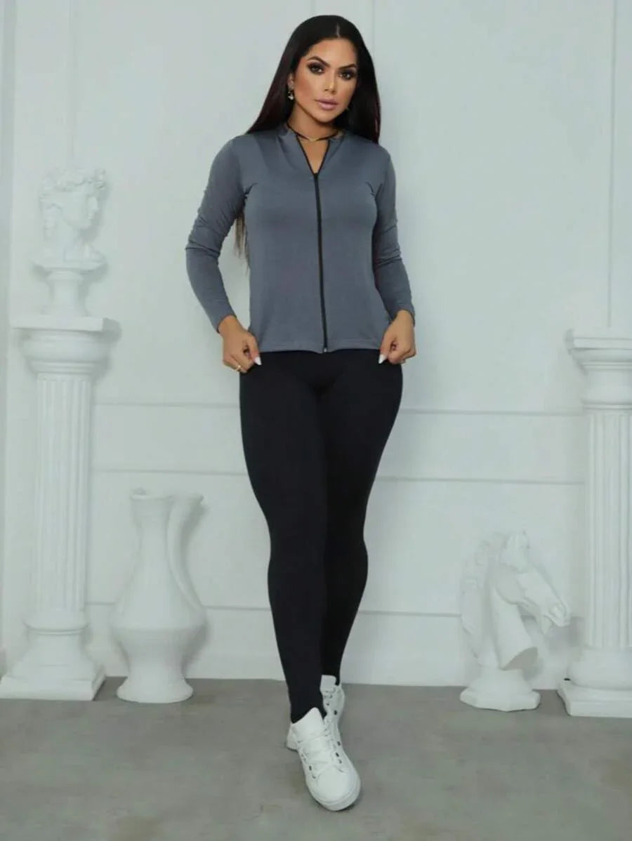 Mulher usando casaco cinza e legging preta com tênis branco, fundo branco fosco com decoração clássica