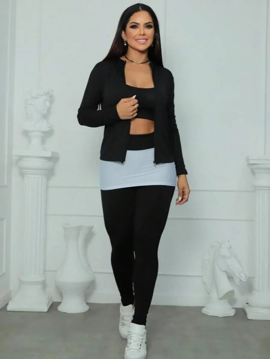 Mulher vestindo conjunto fitness preto com saia cinza em fundo branco fosco e esculturas brancas