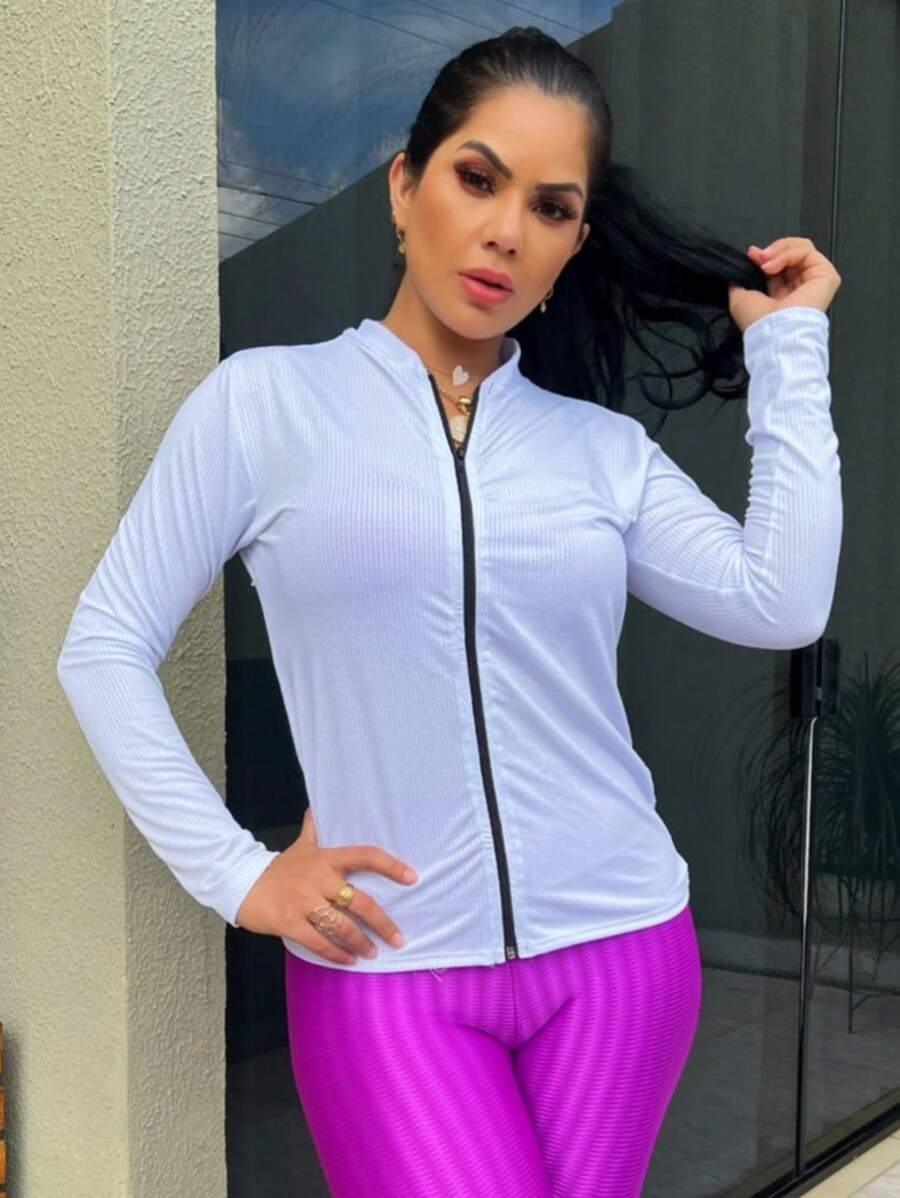 Mulher veste casaco branco com zíper preto e calça legging rosa vibrante, fundo branco fosco
