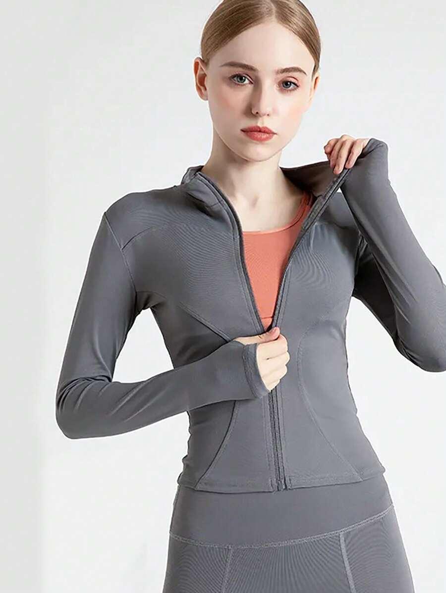 Mulher vestindo jaqueta esportiva cinza com zíper e detalhe em tecido laranja, fundo branco fosco